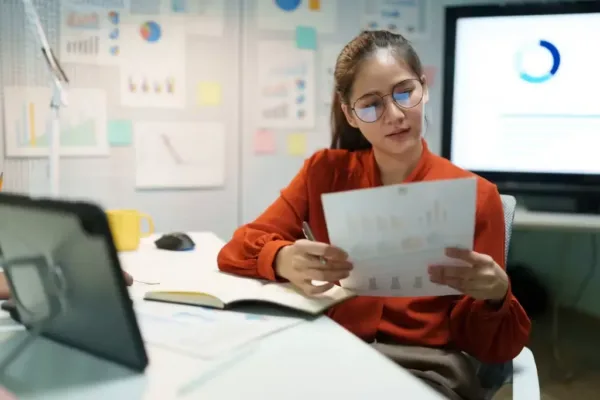 Estudiante frente de computador con papel en mano haciendo referencia a elección de carrera de continuidad de estudios para técnicos